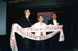 Interior group portrait, From left, Ms. Sarit Zik (Israel), Mr. Fawwaz Momani (Jordan), Mr. Bilal Salameh (Palestine), holding banner reading "McGill Middle East Program in Civil Society and Peace Building."