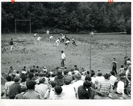Group portrait of boys playing football as spectators look on, Camp Wooden Acres, Montreal.