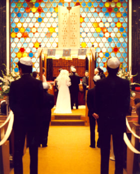 Colour photograph of a wedding in the Sanctuary of the Spanish and Portuguese synagogue, showing the couple under the huppah (wedding canopy)