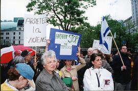 Exterior snapshot of crowd protesting and carrying signs that read "Arretez la violence" and "Arafat, stop the terrorism." Unidentified man at right holds an Israeli flag.
