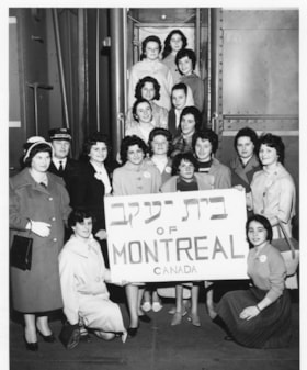 Group of young women from the Bais Yaakov holding a sign outside a train