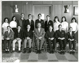 Class photo, interior, Notre-Dame-de-Grâce afternoon school grade six, first row of male students seated on chairs, second row of students standing, male teacher seated in centre of first row.