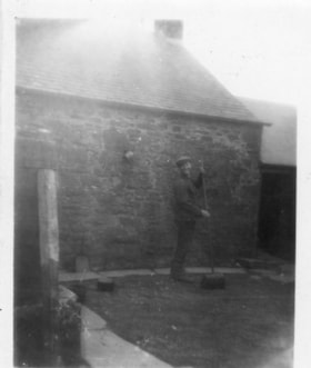 Unidentified man outside a stone house