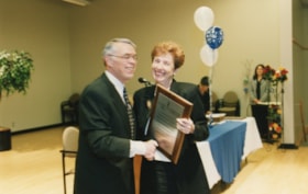 Unidentified woman receives a plaque for the Greenberg Family Libraries Fund from President Norman Lesh