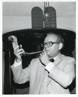 Interior portrait, Rabbi Jay Braverman blowing shofar in front of Aron Hakodesh.