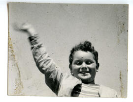 Portrait of a male student with his right arm raised in the air.