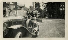 Snapshot of Lila Solomon sitting in car with bouquet of flowers.
