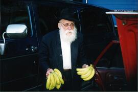 Exterior snapshot of Benny Kaplan carrying bananas to give to the poor, from the documentary film "Keepers of the Faith: Canadian Chasidim" by Ian McLaren.
