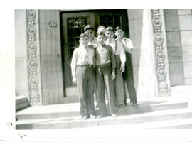Exterior group portrait, male students standing on steps in front of a building.